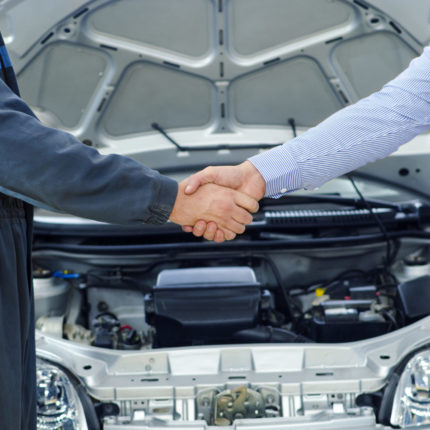 Car mechanic and customer shaking hands.